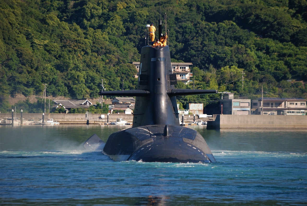 A submarine with crew on the top in the water before a grass landing.