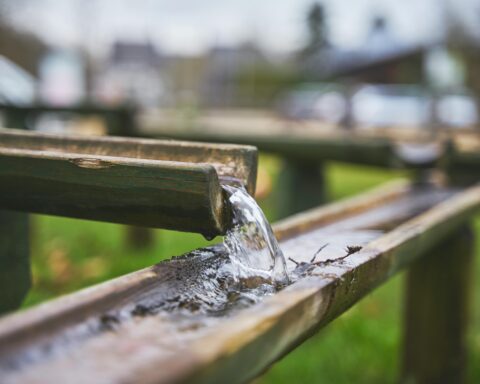 Water pours from an elevated gutter into a lower gutter.