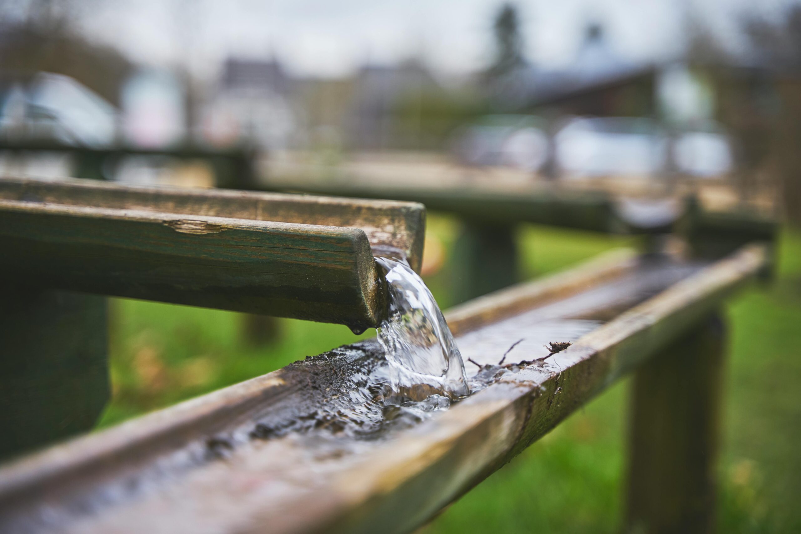 Water pours from an elevated gutter into a lower gutter.