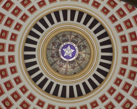 The Oklahoma seal is depicted within an artistic pattern outward with gold, red, black and white hues.