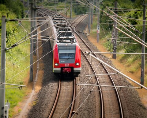 A train on rail tracks in between trees and green grass.