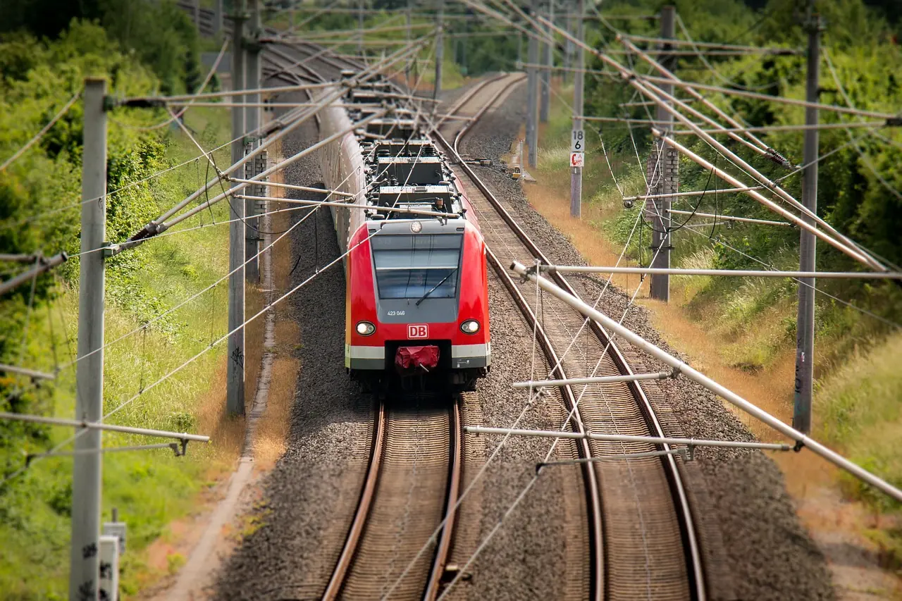 A train on rail tracks in between trees and green grass.