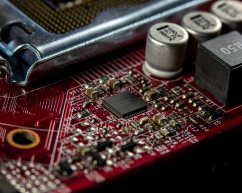A close up image of a red motherboard with conductors and semiconductors.