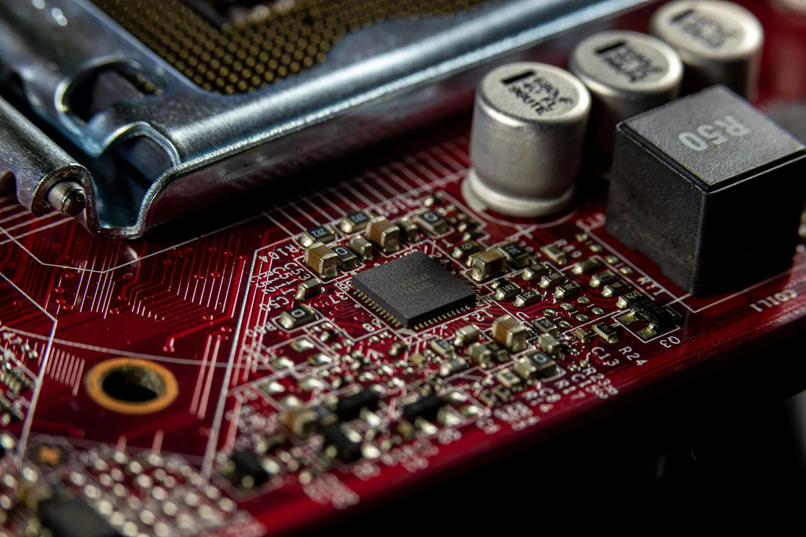 A close up image of a red motherboard with conductors and semiconductors.