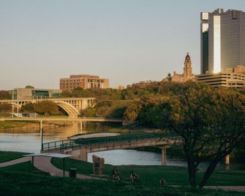 A bridge, grass and several buildings along the Trinity River in Fort Worth, Texas.