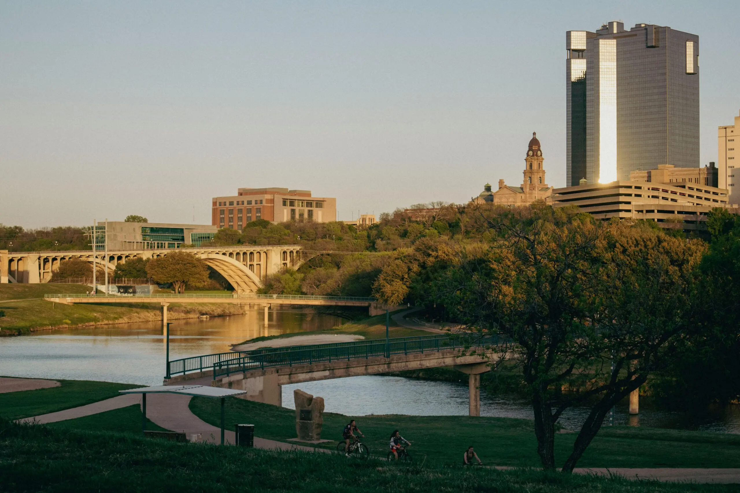 A bridge, grass and several buildings along the Trinity River in Fort Worth, Texas.