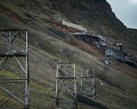 An abandoned mine along a green and black hill.