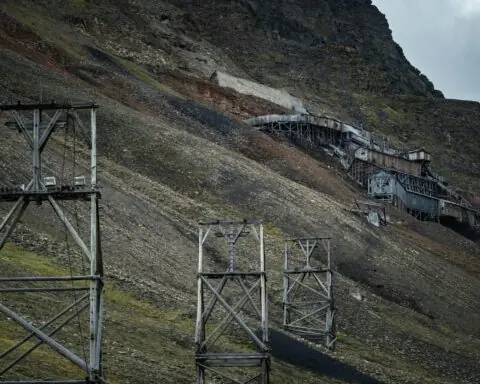 An abandoned mine along a green and black hill.