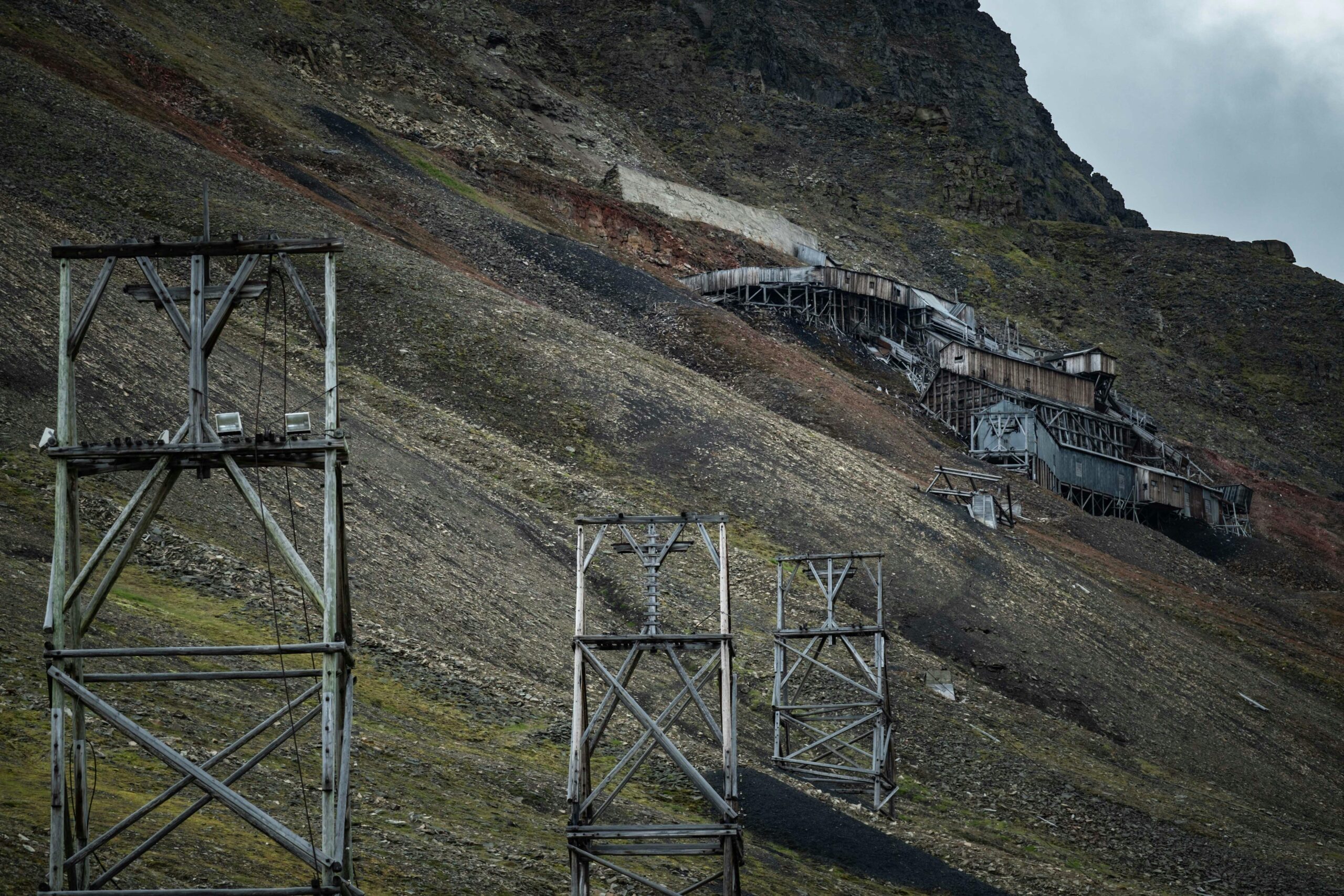 An abandoned mine along a green and black hill.