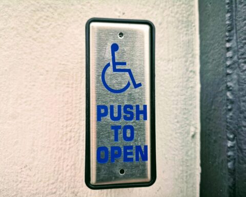 An accessibility button on a wall indicating that if one were to push the button, a door would open.
