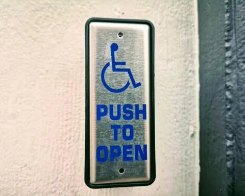 An accessibility button on a wall indicating that if one were to push the button, a door would open.