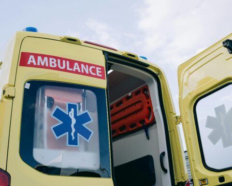 A yellow ambulance with its rear door open.