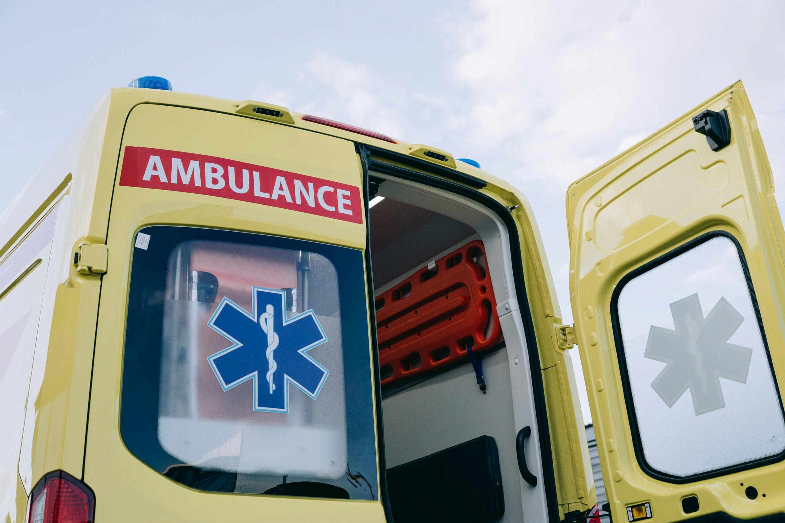 A yellow ambulance with its rear door open.