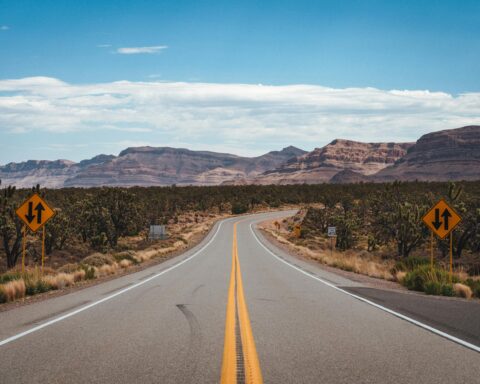 A highway in Arizona leads to distant rock formations and desert.