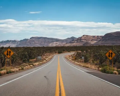 A highway in Arizona leads to distant rock formations and desert.
