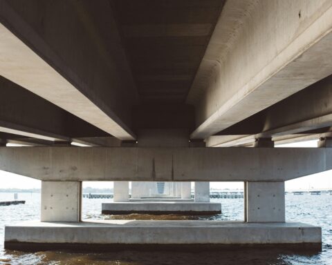 The underside of a bridge above water.