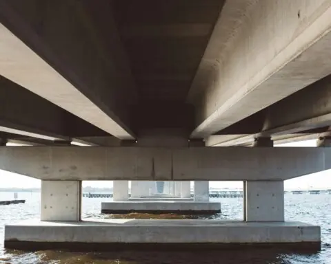 The underside of a bridge above water.