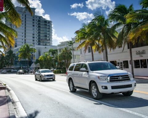 Two cars on a Florida road surrounded by buildings and palm trees.