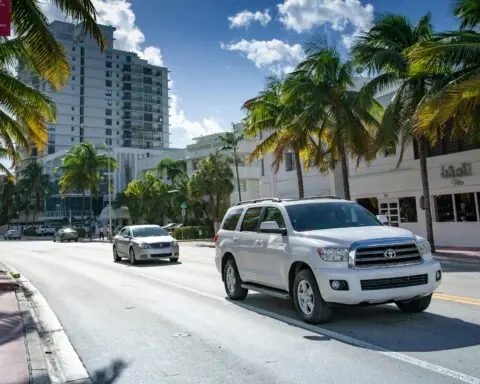 Two cars on a Florida road surrounded by buildings and palm trees.