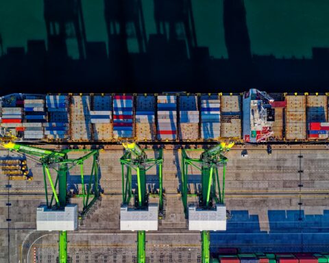 A container ship docks at a port from above.