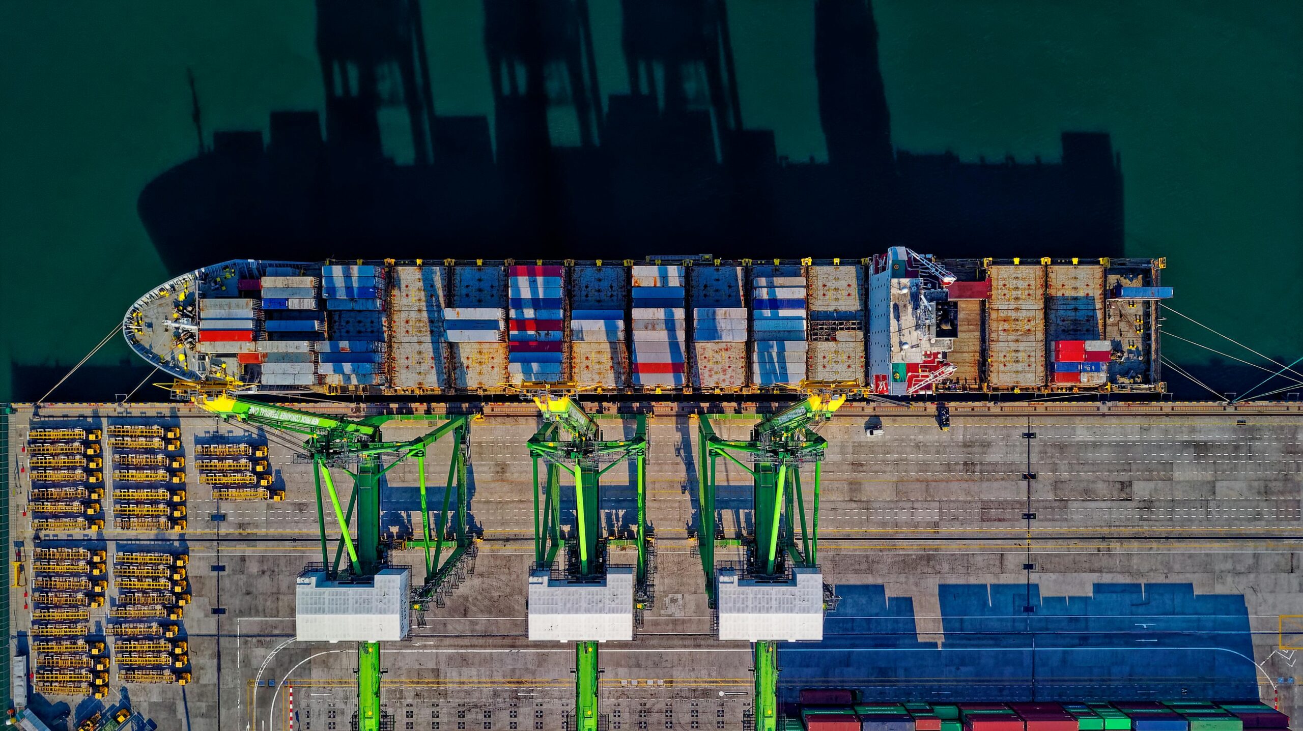 A container ship docks at a port from above.