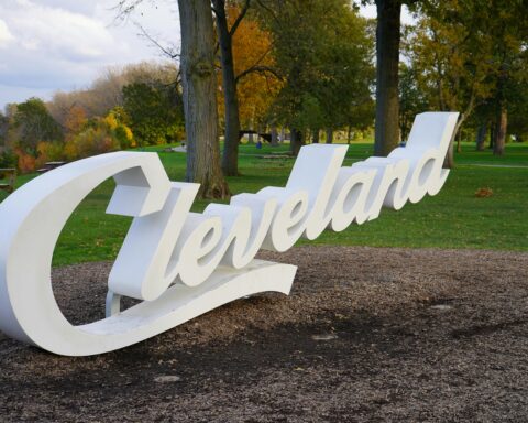 A sign saying Cleveland in a dirt patch next to trees in Ohio.