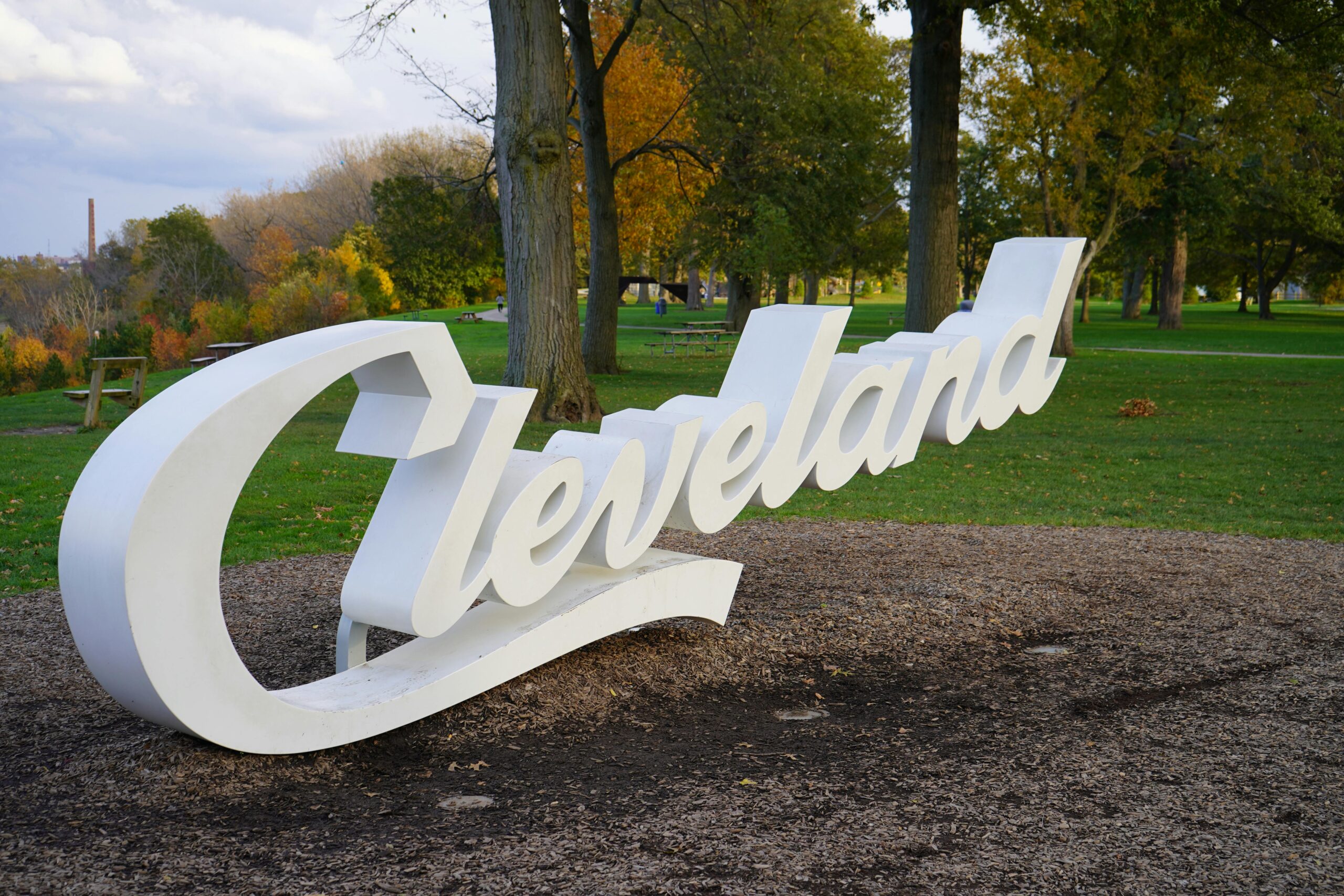 A sign saying Cleveland in a dirt patch next to trees in Ohio.