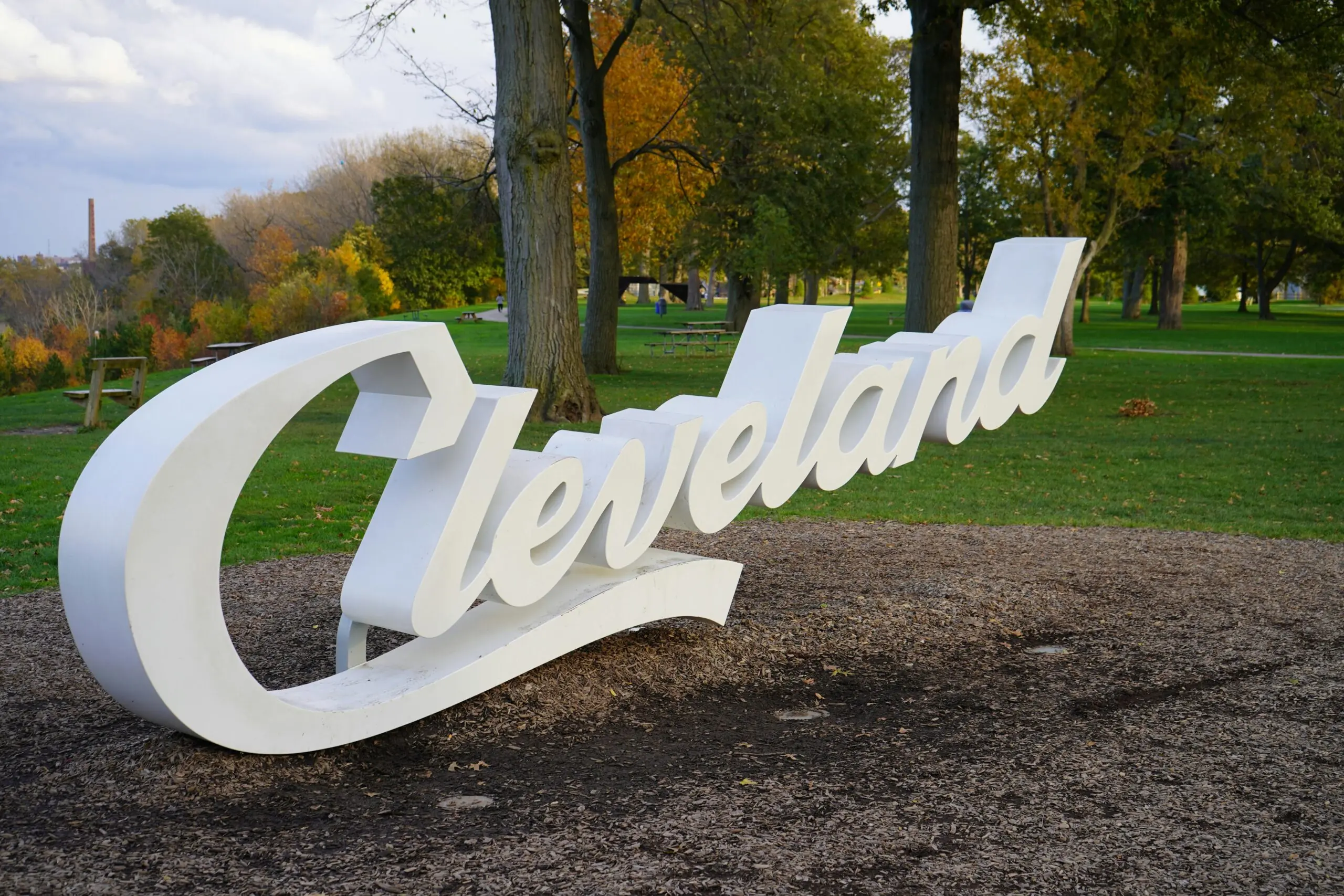 A sign saying Cleveland in a dirt patch next to trees in Ohio.