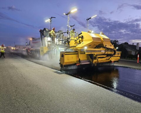 A construction vehicle repaves a roadway.