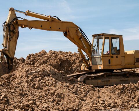 A construction vehicle on a work site on a pile of dirt.