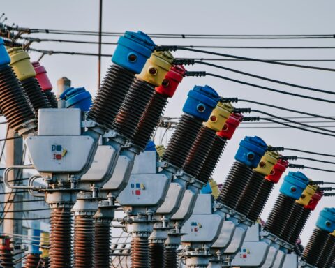 A close up image of several electric transformers and related electric poles and wires.
