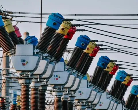 A close up image of several electric transformers and related electric poles and wires.