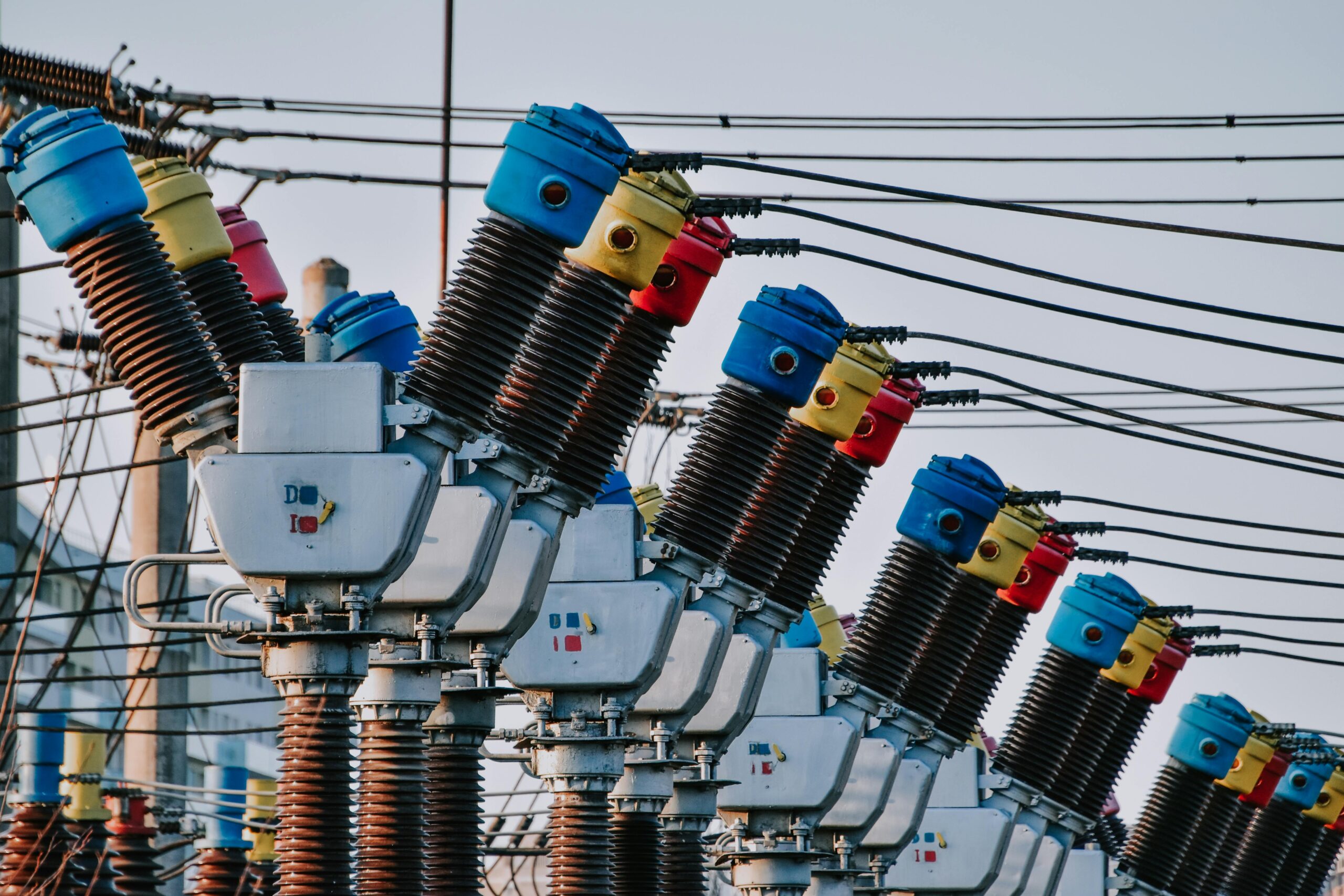 A close up image of several electric transformers and related electric poles and wires.