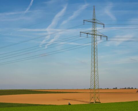An energy line in green and brown fields beneath a blue sky.