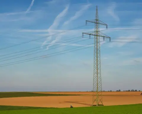 An energy line in green and brown fields beneath a blue sky.