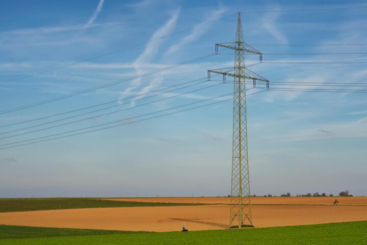 An energy line in green and brown fields beneath a blue sky.