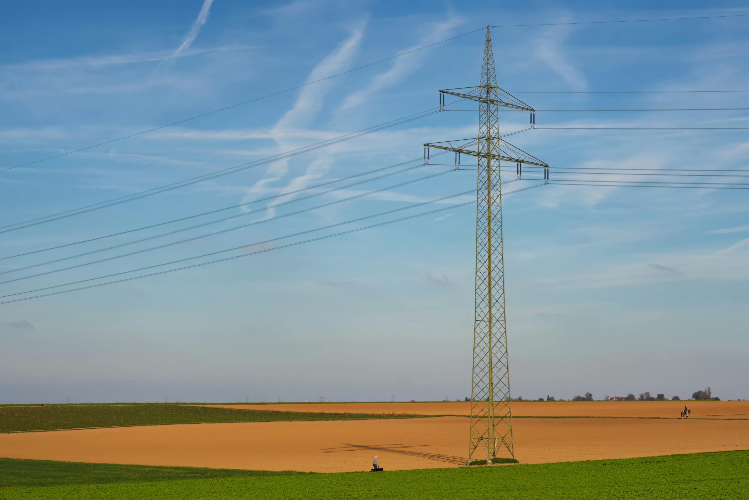An energy line in green and brown fields beneath a blue sky.
