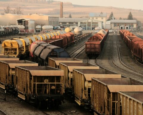Trains sit on rails at a railyard.