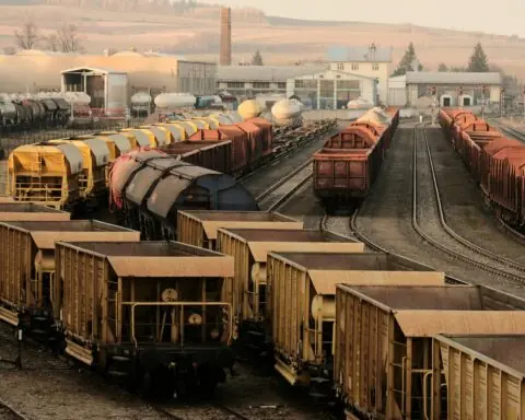 Trains sit on rails at a railyard.