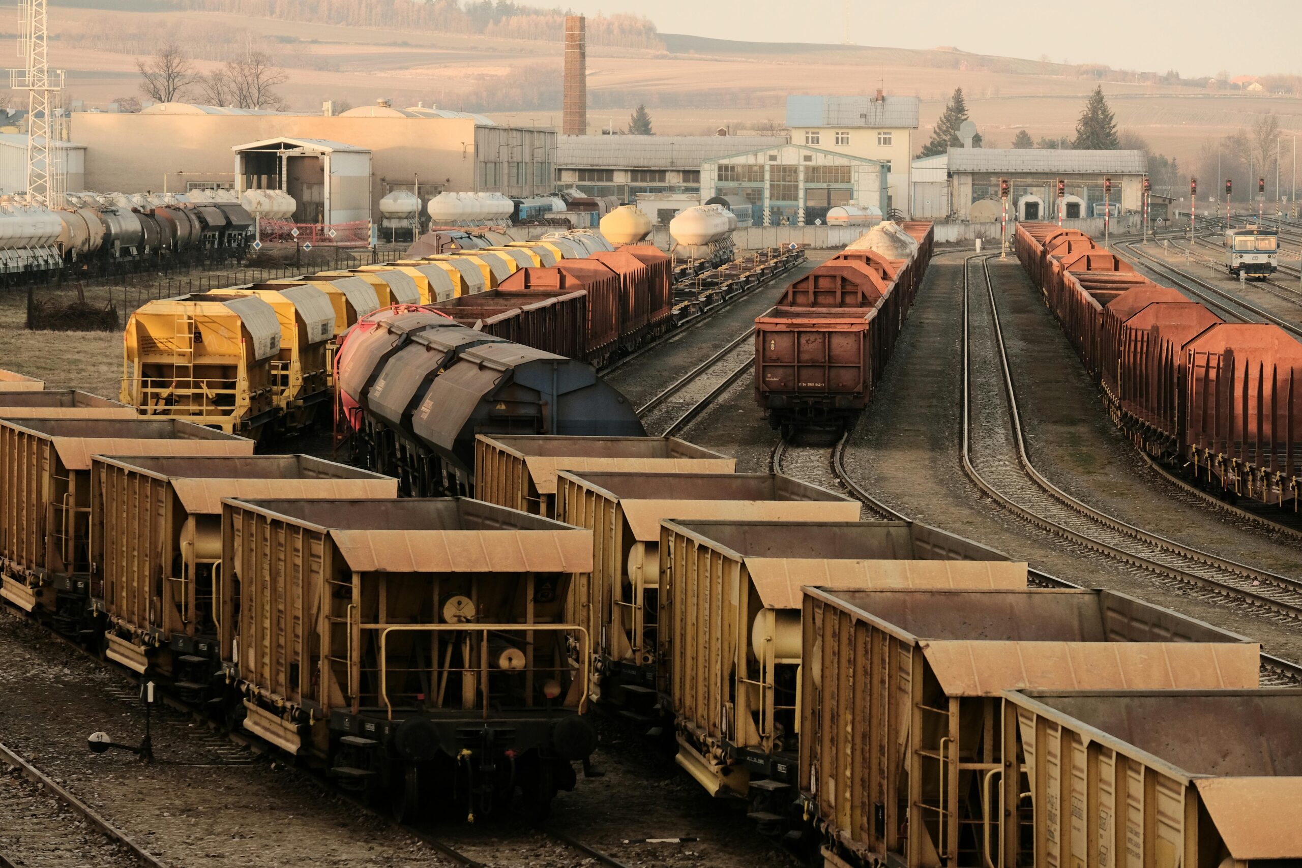 Trains sit on rails at a railyard.