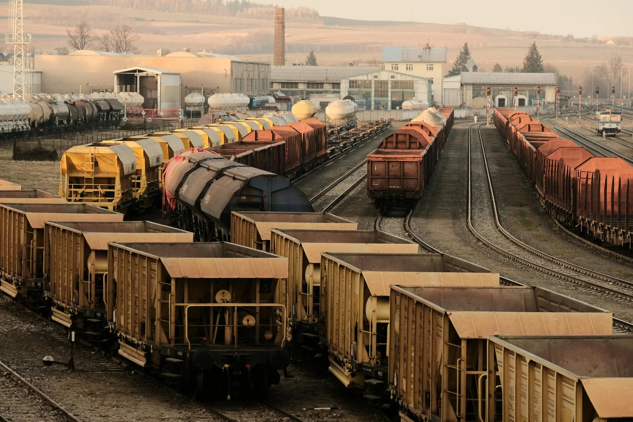 Trains sit on rails at a railyard.