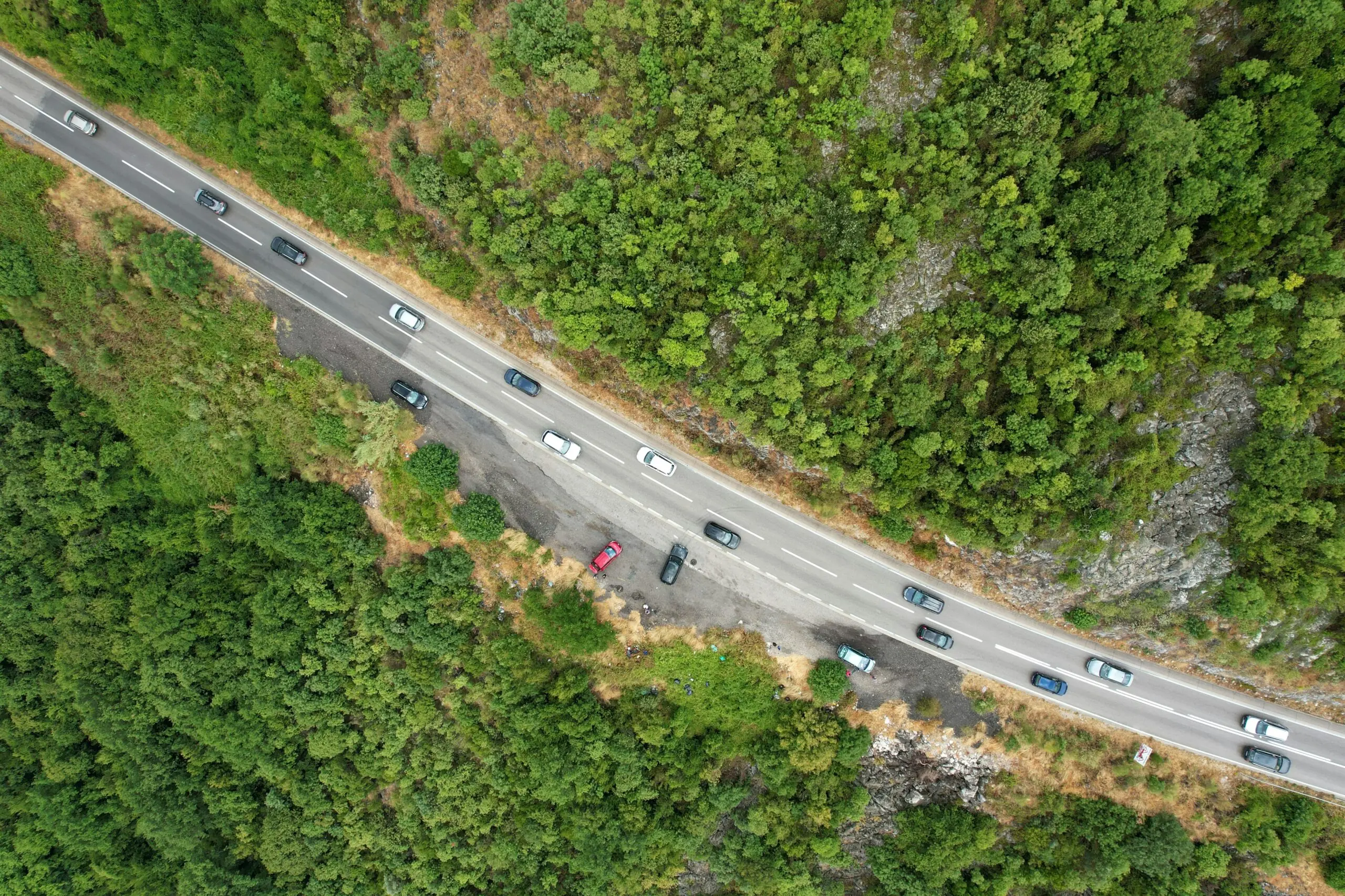 An aerial view of a long highway in between trees.