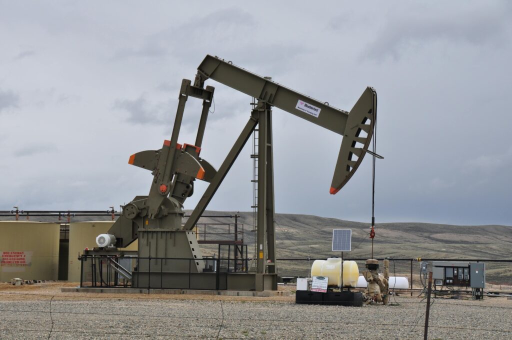 An oil extractor in an empty field extracting oil and gas from the ground.