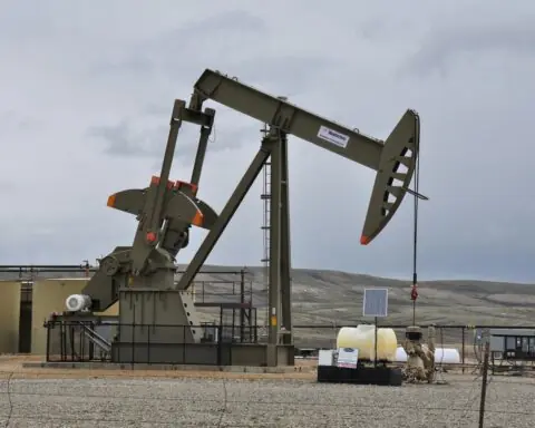 An oil extractor in an empty field extracting oil and gas from the ground.