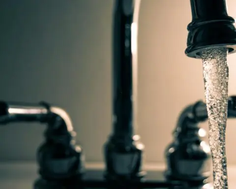 Water pours out of a metal faucet.
