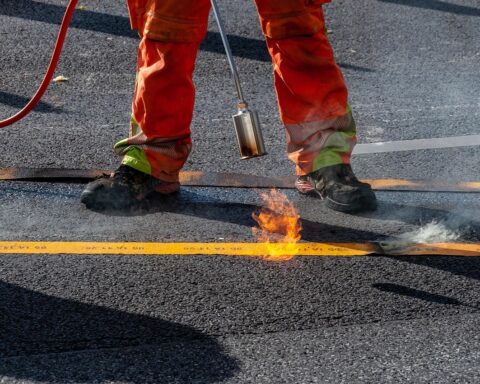 A construction worker ignites a blow torch to a road.