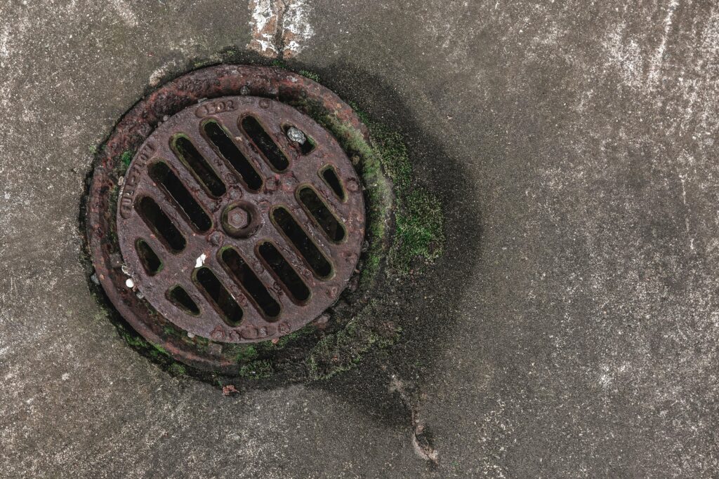 A sewer grate from above on an asphalt street.