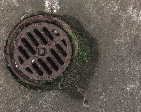 A sewer grate from above on an asphalt street.