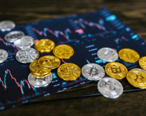 Silver and gold coins with a Bitcoin logo on top of a tablet with pricing ladders.