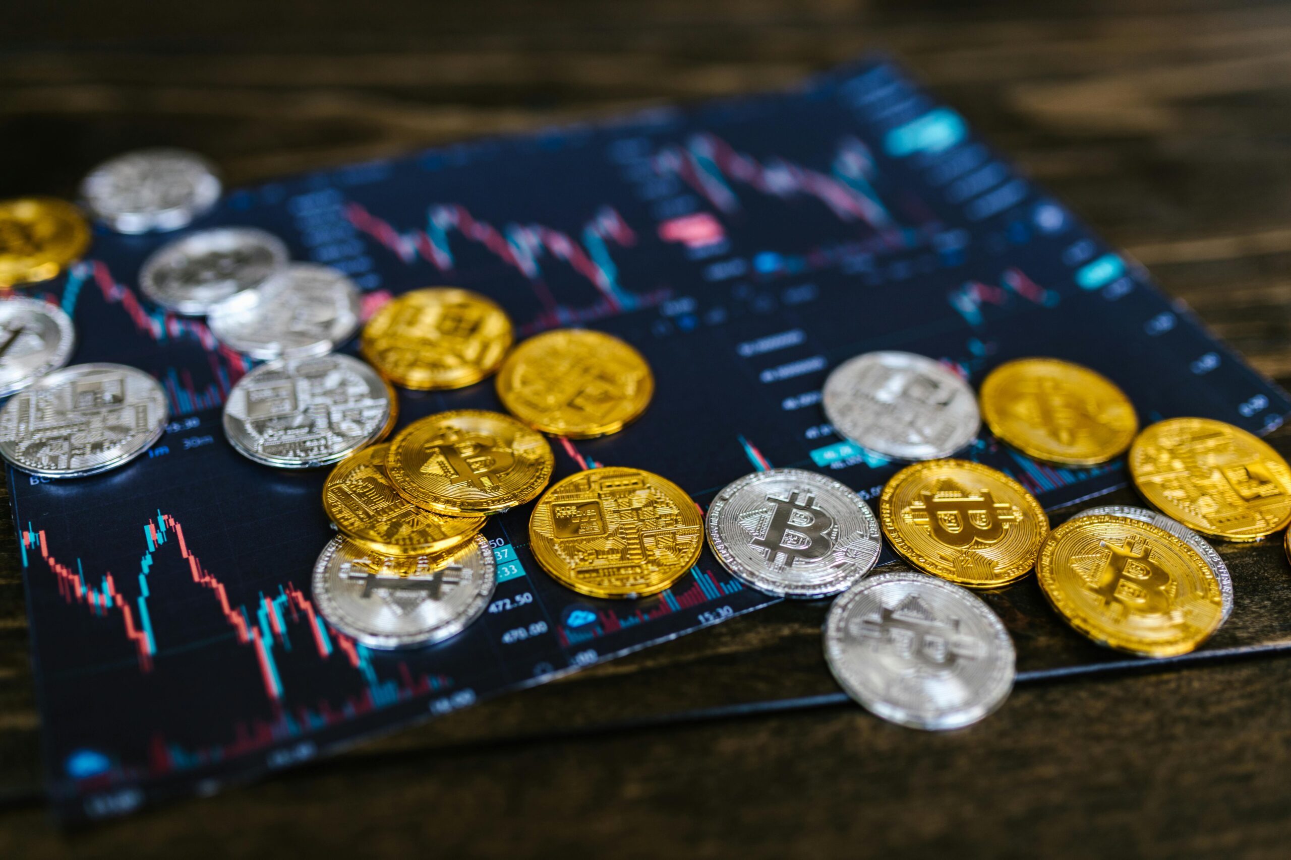 Silver and gold coins with a Bitcoin logo on top of a tablet with pricing ladders.